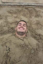 man buried in the sand on a beautiful beach