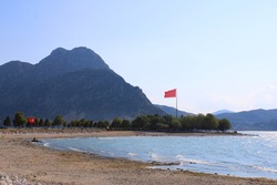 Beach of Egirdir Lake in Isparta, Turkey. Two Turkish flag. Mountain in background.