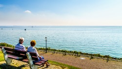 Senior couple enjoying a rest and view of the inland sea named IJselmeer with its wind farms from the historic fishing village of Urk in the Netherlands