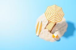 Tropical vacation background. Sun lounger with umbrella and beach accessories for active rest on the sandy island, copy space, top view