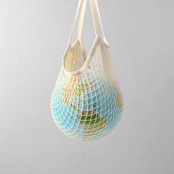 World globe in crochet bag, floating in air on light gray background. Eco-friendly life in the style of zero waste. Earth day, save the planet.