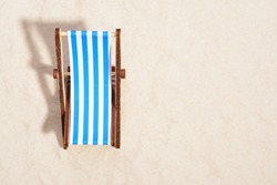 Top view of wooden beach chair on beach.
