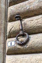 Close up of an iron ring (or hitching post) used in ancient times to tie horses and to hold fire lamps, on a wall of a medieval building in Florence city center, Tuscany region, Italy