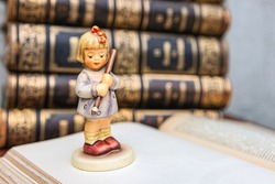 Pretty girl  figurine on old book background. Student figurine on an  book. First grader. Beginning of the school year