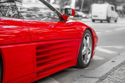 Red sports car on city streets, black and white background
