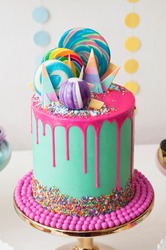 Neon green and pink drip happy birthday cake by Katherine Sabbath topped with assorted rainbow coloured lollipop swirls and candy shards