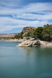 Spectacular panoramic views of the Guadalhorce reservoir, next to the Caminito del Rey in Malaga, Andalusia, Spain. Turquoise blue water and forest with blue sky on a sunny day.