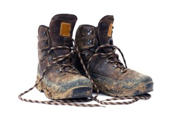 Hiking boots, well worn and muddy, isolated on white.