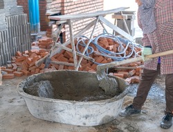 Mixing mortar in a mortar mixer for floor tile in building site.