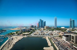 Abu Dhabi skyline with air show colors in the sky and view of the downtown modern buildings of the UAE capito
