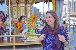 Happy beautifull girl stands in front of a carousel in a amusement park