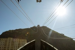 Rio de Janeiro, Brazil. Urca Hill with sun shining and blue sky in the morning and cable car cables in perspective.