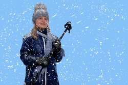 A girl in the winter stands on skis under the snow. Child in outerwear goes in for sports outdoors.