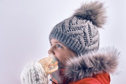 Girl eating burger outdoors in winter. Street food. A child in outerwear eats fast food.