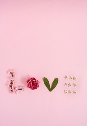 Spring  creative love arrangement made of fresh pink and white blossoming twigs, flowers and leaves on a pastel pink background with copy space. Flat lay minimal concept.