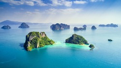 Surrounding Islands of Koh Yao Noi, Phuket, Thailand green lush tropical island in a blue and turquoise sea with islands in the background and clouds with sun beams shining through, drone aerial photo