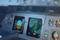 Commercial passenger aircraft cockpit flight instruments view including attitude indicator, altimeter, navigation display and speed indicator