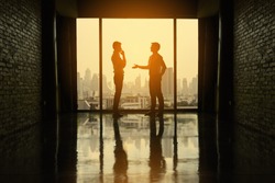 Two businessmen are negotiating business in office on the building.
Two businessmen business negotiations.(Silhouette)
