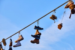 Old Shoes hanging on electrical wire against a sky
