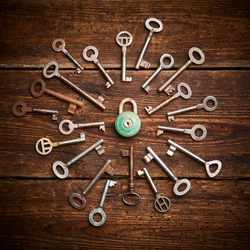 Vintage rusty padlock surrounded by group of old keys on a weathered wooden background. Internet security and data protection concept, blockchain and cybersecurity.   Escape route and room game sign