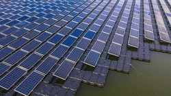 Solar farm panels in aerial view, rows array of polycrystalline silicon solar cells or photovoltaics in solar power plant floating on the water in lake, Alternative renewable energy.