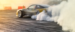 Blurred car drifting on asphalt racing track with lot of smoke, motion blur drift car.
