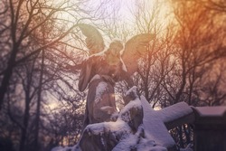 Angel statue illuminated by sunlight. Cemetery during the winter