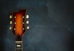 Close-up of headstock old electric jazz guitar on a dark blue background with copy space