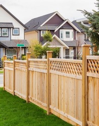 Nice wooden fence around house. Wooden fence with green lawn and trees. Street photo, nobody, selective focus