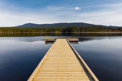 Idyllic view of the wooden pier in the lake with mountain scenery background in the early morning. Natural background, nobody, travel photo, copy space for text