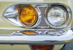 Vintage Car Front Detail. Classic car headlights close-up. Headlights of yellow vintage car. Exhibition. Nobody, street photo, selective focus, blurred