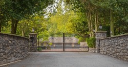 Iron front gate of a luxury home. Wrought iron gate and brick pillar. Nobody, street photo, selective focus