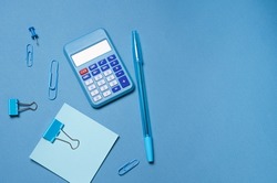 Calculator, stationery accessories on blue background with copy space. Look, school accessories for children's education and development. Office tools