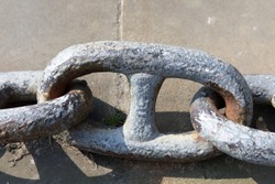 Large Chain links laying on stone, one large chain link with two chain links either side.