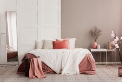 Orange pillows on white king size bed in fashionable female bedroom