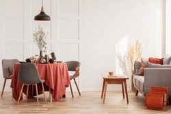 Living and dining room interior with grey couch and table covered with orange tablecloth