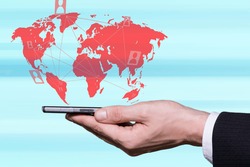 Male hand holding smartphone and world map in background