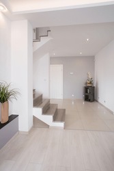 White clean hallway with wooden stairs on the first floor