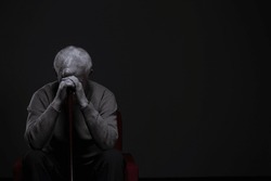 Depressed old man hiding his face behind hands