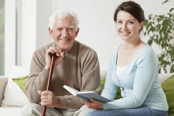 Old man holding cane and young woman reading a book
