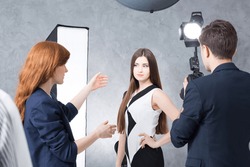 Shot of a young woman explaining a model what to do during the fashion photoshoot