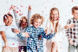 Happy kids throwing colorful confetti in a room
