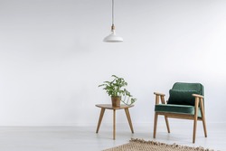 Old fashioned green armchair in white simple room