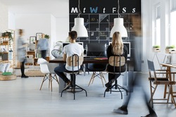 People in modern coworking space with blackboard calendar