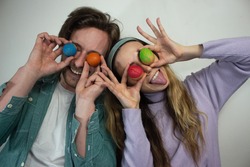 Picture of young couple having fun with painted Easter eggs at home. Concept couple Happy Easter. Young couple with colorful outfit holding painted eggs doing funny faces.
