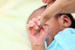 Newborn baby boy gripping mothers finger