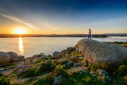 Man standing on the edge of the rock at sunset. View from Granite Island, South Australia