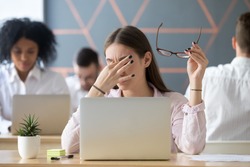 Young woman taking off glasses tired of computer work, exhausted student or employee suffering from eye strain tension or computer blurry vision problem after long laptop use, eyes fatigue concept