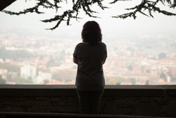 Rear view at thoughtful woman silhouette standing at view point looking at city watching urban cityscape vision pondering over question or problem, contemplating thinking of future loneliness concept