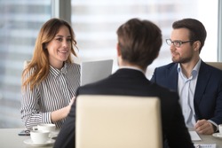 Young broker businesswoman talking to business partners. Woman consulting, giving instructions, explaining terms of contract. Man in glasses looking colleague and listening.
